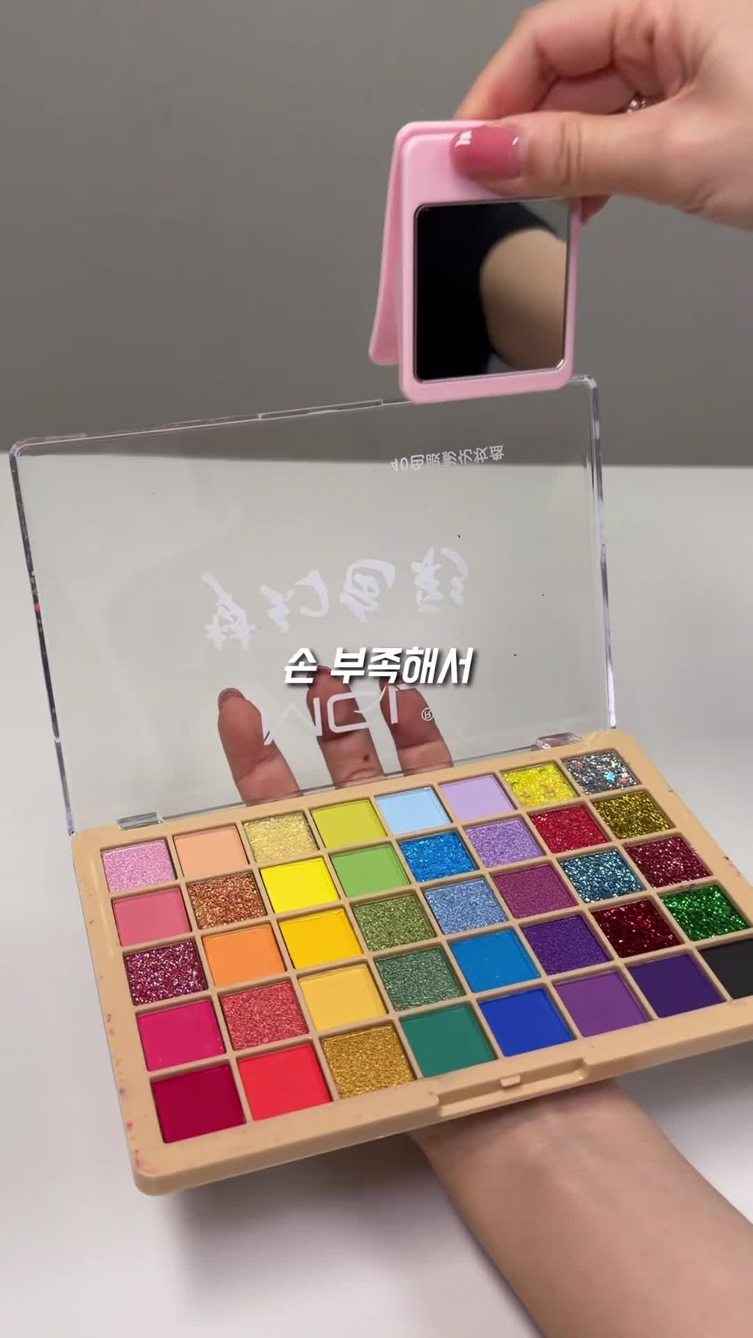 먹통령 영상에서 40색 아이섀도 팔레트 뚜껑에 다이소 집게거울을 고정하는 모습